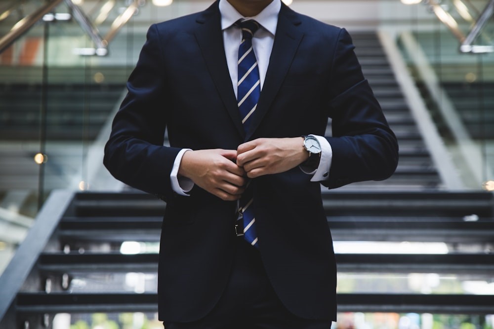 A man in a suit standing near the stairs