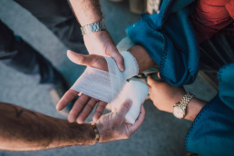 A person is applying a bandage on another person’s hand