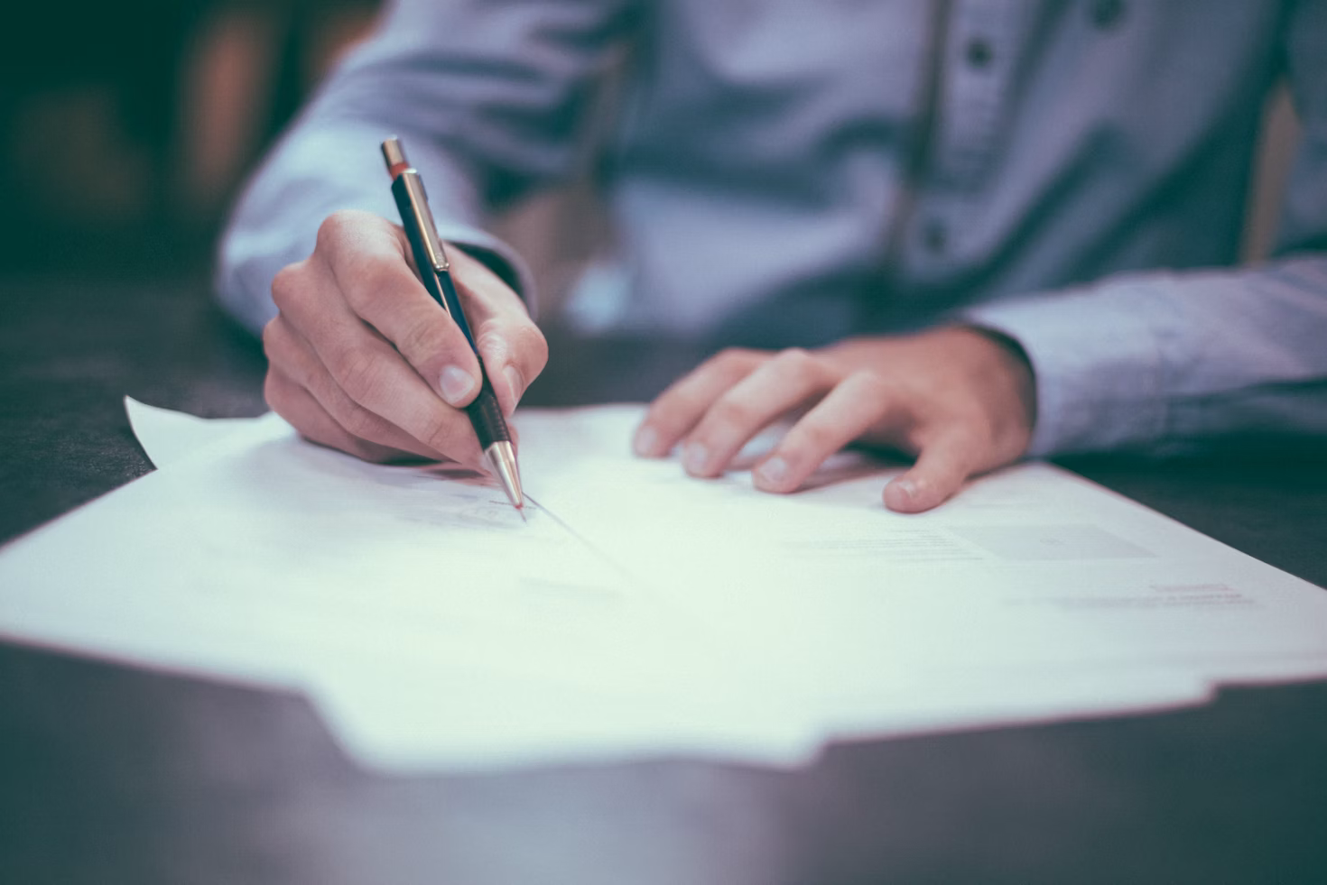 a person in a blue shirt signing an insurance settlement agreement