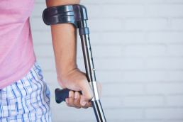 A person holding a crutch and walking cane symbolizes the impact of medical malpractice injuries.